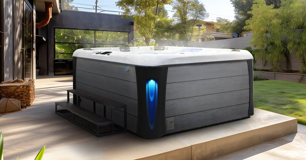 A Cal Spas hot tub with lime oak cabinet and blue lighted corners on a wooden patio.